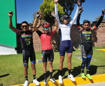 Cuatro ciclistas con las manos levantadas luego de participar en la carrera ciclista