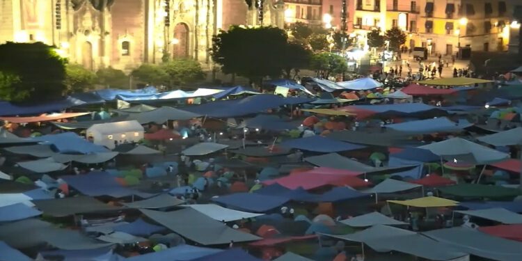 Un zócalo tapizado de hules de color, mecates y tendidos se observa hoy por la noche en la capital de la República.