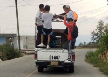 Los usuarios prefieren viajar colgados en los carros que transportan pasaje.