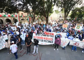 Jóvenes embozados recordaron a los 43 normalistas de Ayotzinapa con una marcha por las calles de la capital oaxaqueña.