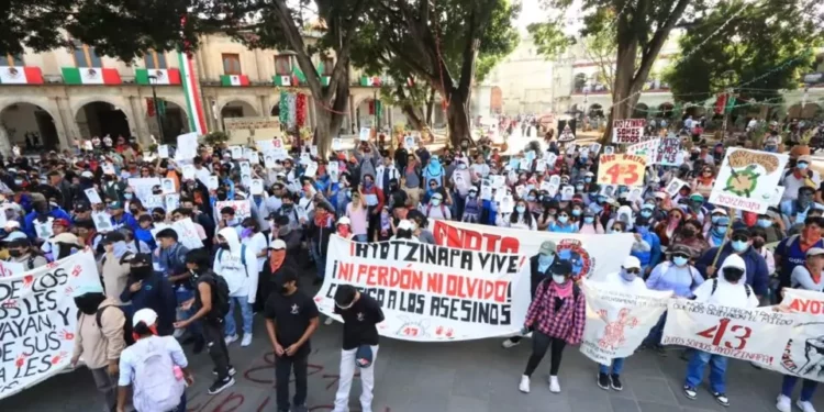 Jóvenes embozados recordaron a los 43 normalistas de Ayotzinapa con una marcha por las calles de la capital oaxaqueña.