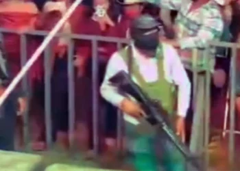 En la zona de seguridad entre el escenario y el público, permanecen varias personas con uniforme, pasamontañas y portando rifles de alto poder.