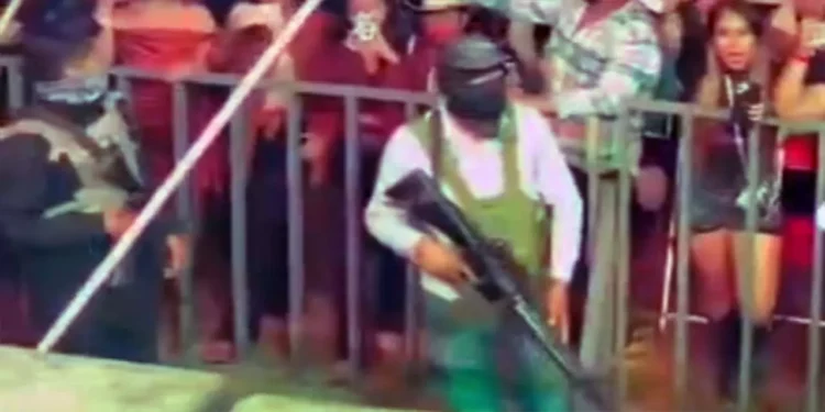 En la zona de seguridad entre el escenario y el público, permanecen varias personas con uniforme, pasamontañas y portando rifles de alto poder.
