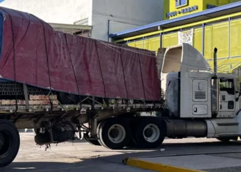 Bomberos evalúan los daños en la estructura de Telmex que quedó sostenida únicamente por los cables de alta tensión.