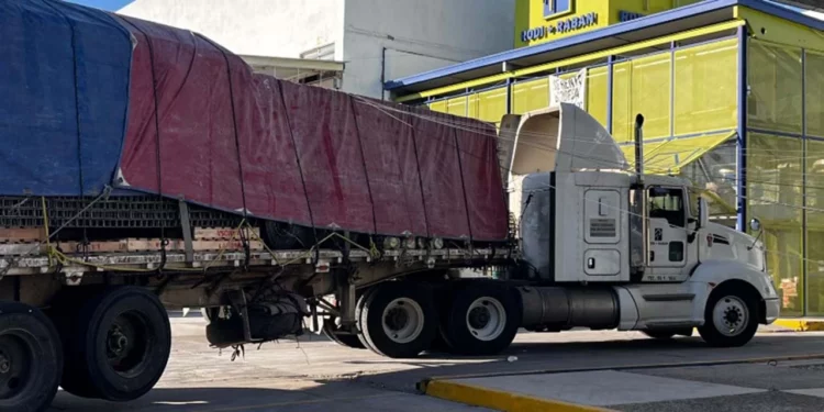Bomberos evalúan los daños en la estructura de Telmex que quedó sostenida únicamente por los cables de alta tensión.