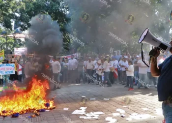 Foto: Adrián Gaytán // Burócratas queman las gorras entregadas por la dirigencia sindical para la movilización por el Día del Trabajo.