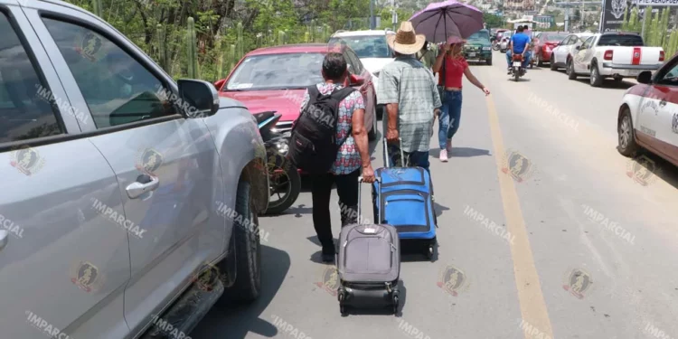Fotos: Adrián Gaytán // Pasajeros aéreos obligados a caminar por el bloqueo magisterial.