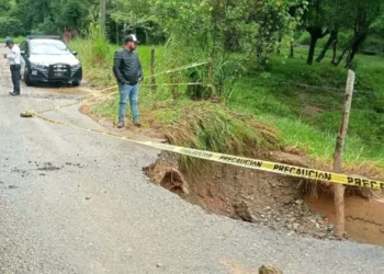 Cuadrillas de emergencia y la Policía Vial revisan un socavón en la carretera.