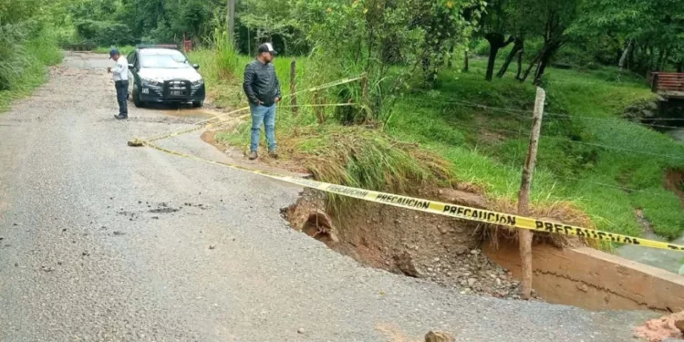 Cuadrillas de emergencia y la Policía Vial revisan un socavón en la carretera.